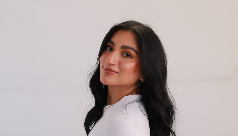 Retrato de estudio de Camila Quiroga sonriendo sobre fondo blanco